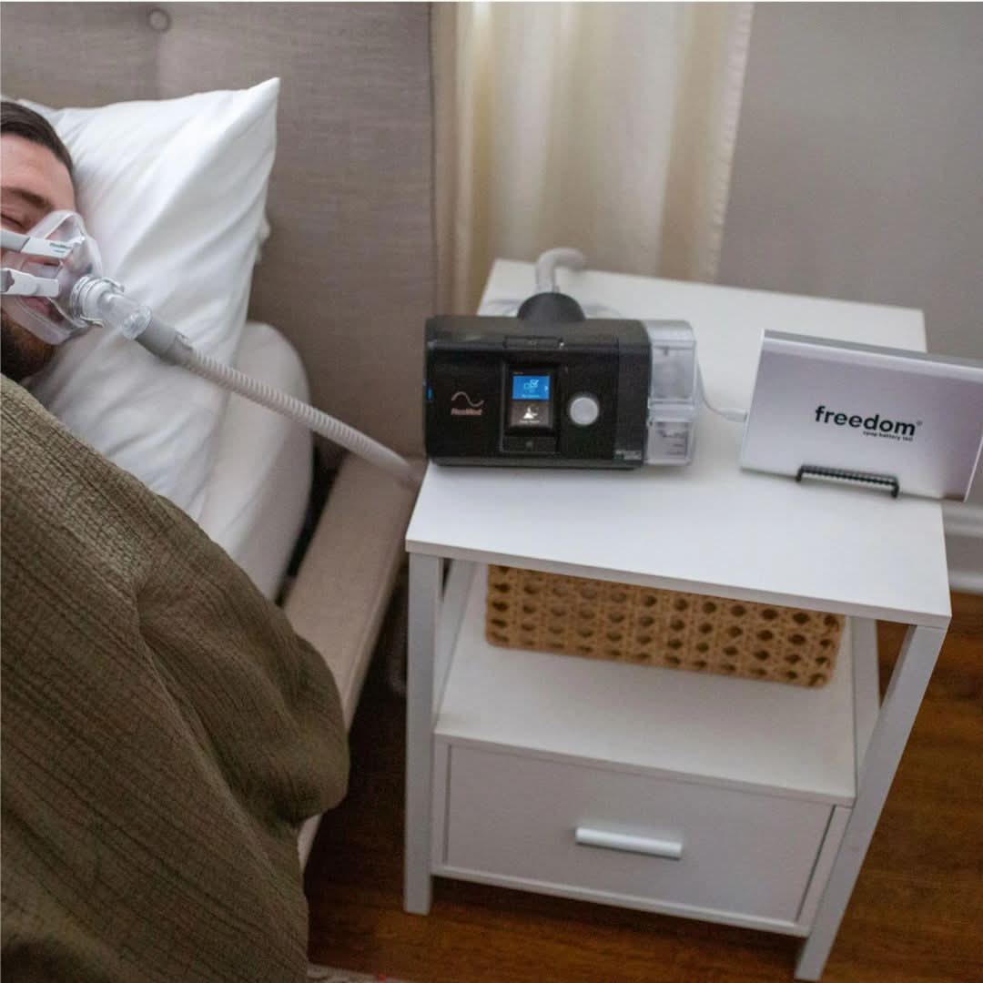 Freedom CPAP Battery 160 Kit, a compact and portable power source for CPAP and BiPAP devices, ensuring up to 51 hours of run time on a single charge. Includes 12V/24V cables, a power supply, and a USB port for charging small electronics.